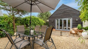 A patio with a table and chairs, a large umbrella, and a small shed with glass doors. - Buff Lodge - sleeps 4 guests in 2 bedrooms (Near Oxford)