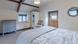 Ein Schlafzimmer mit Bett, Schminktisch, Stuhl und einer Tür mit Fenster.