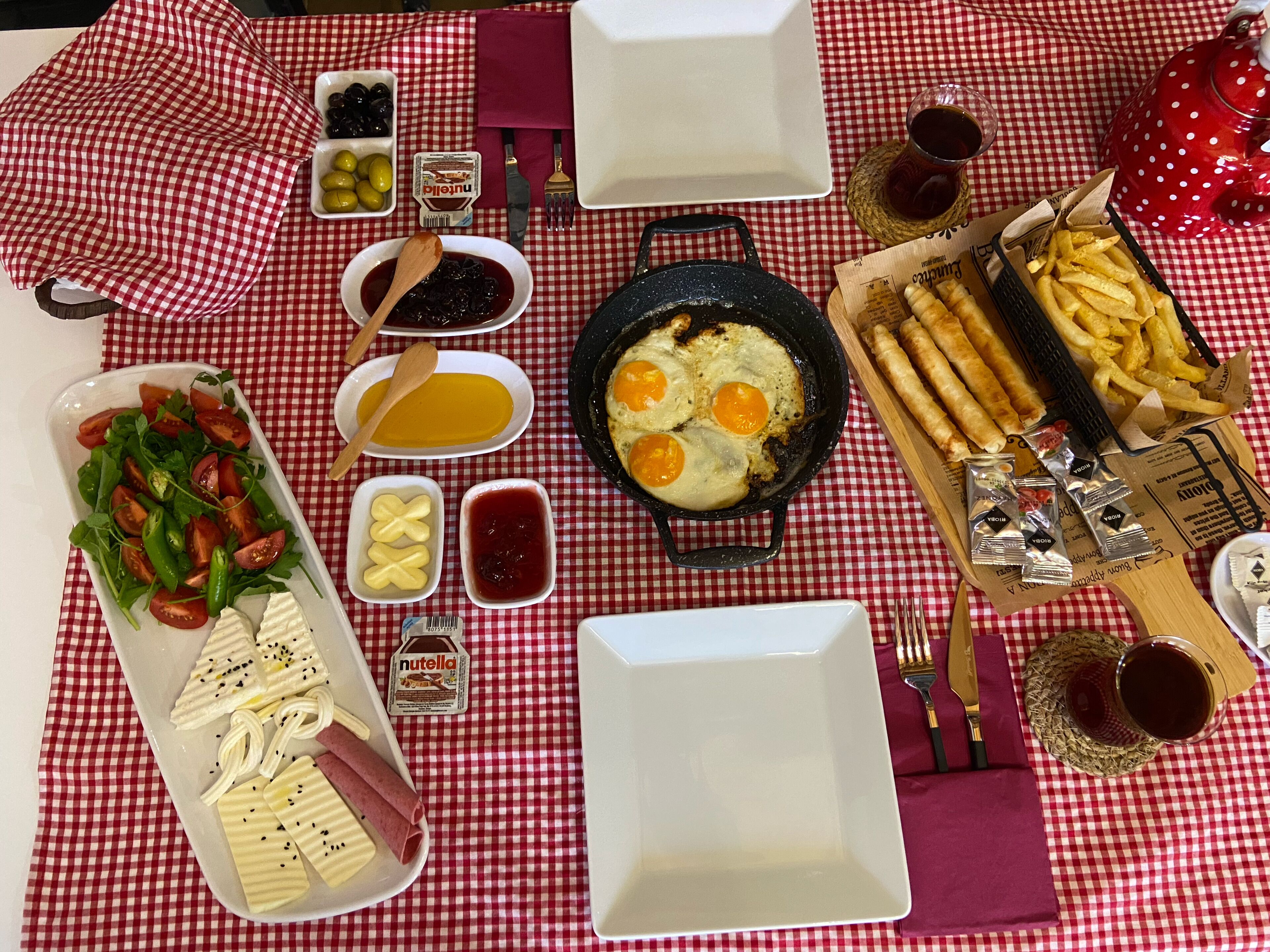 Una tavola apparecchiata con diversi cibi per la colazione, tra cui uova, pane tostato e un'insalata, accompagnati da condimenti e bevande.
