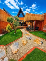 Una casa moderna con techo de paja, un camino de piedra y un césped bien cuidado.