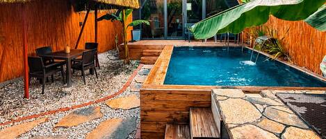 A modern villa with a swimming pool, wooden deck, and tropical vegetation.