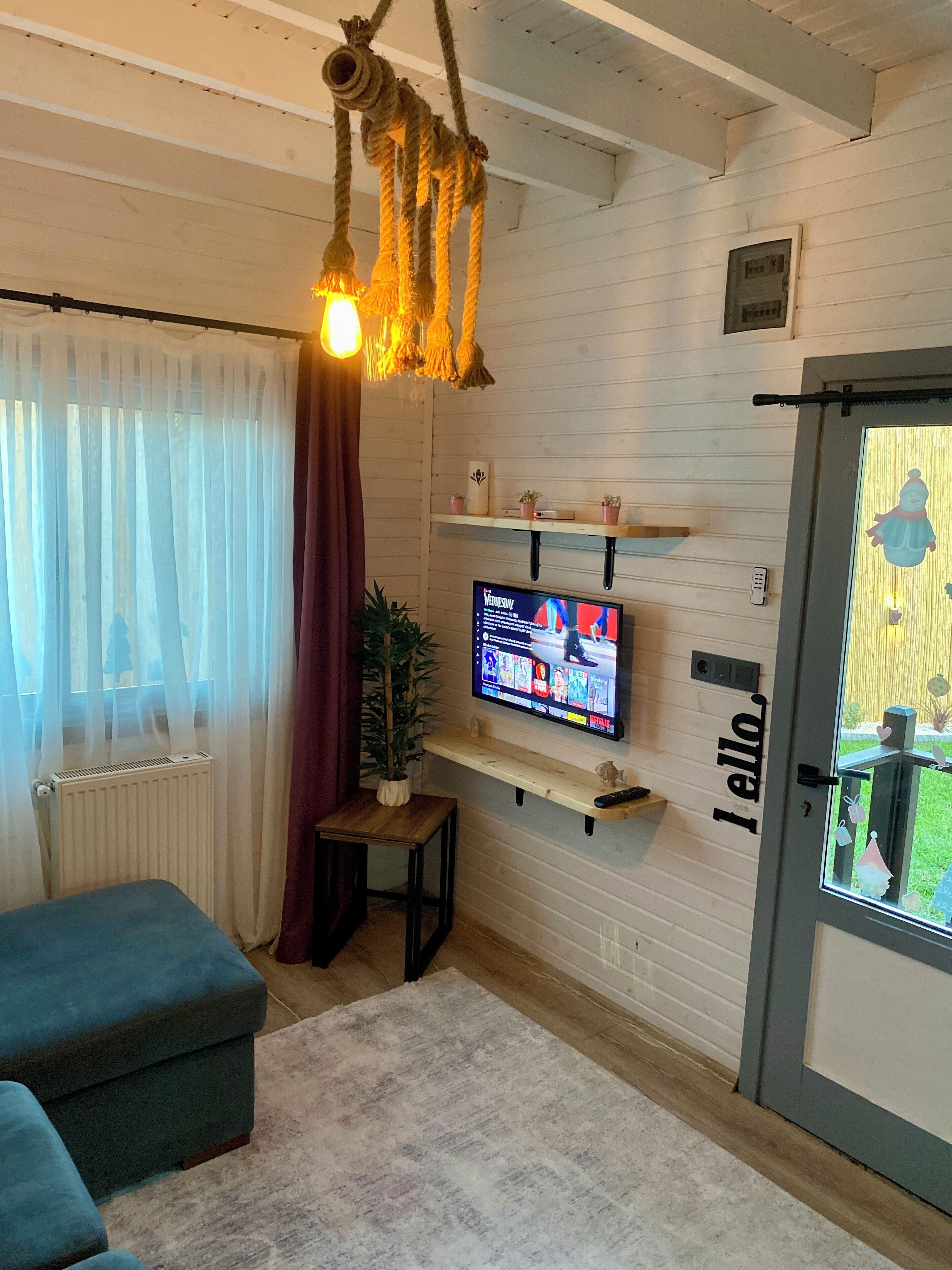 A cozy living room with a television, a plant, and a hanging light fixture.