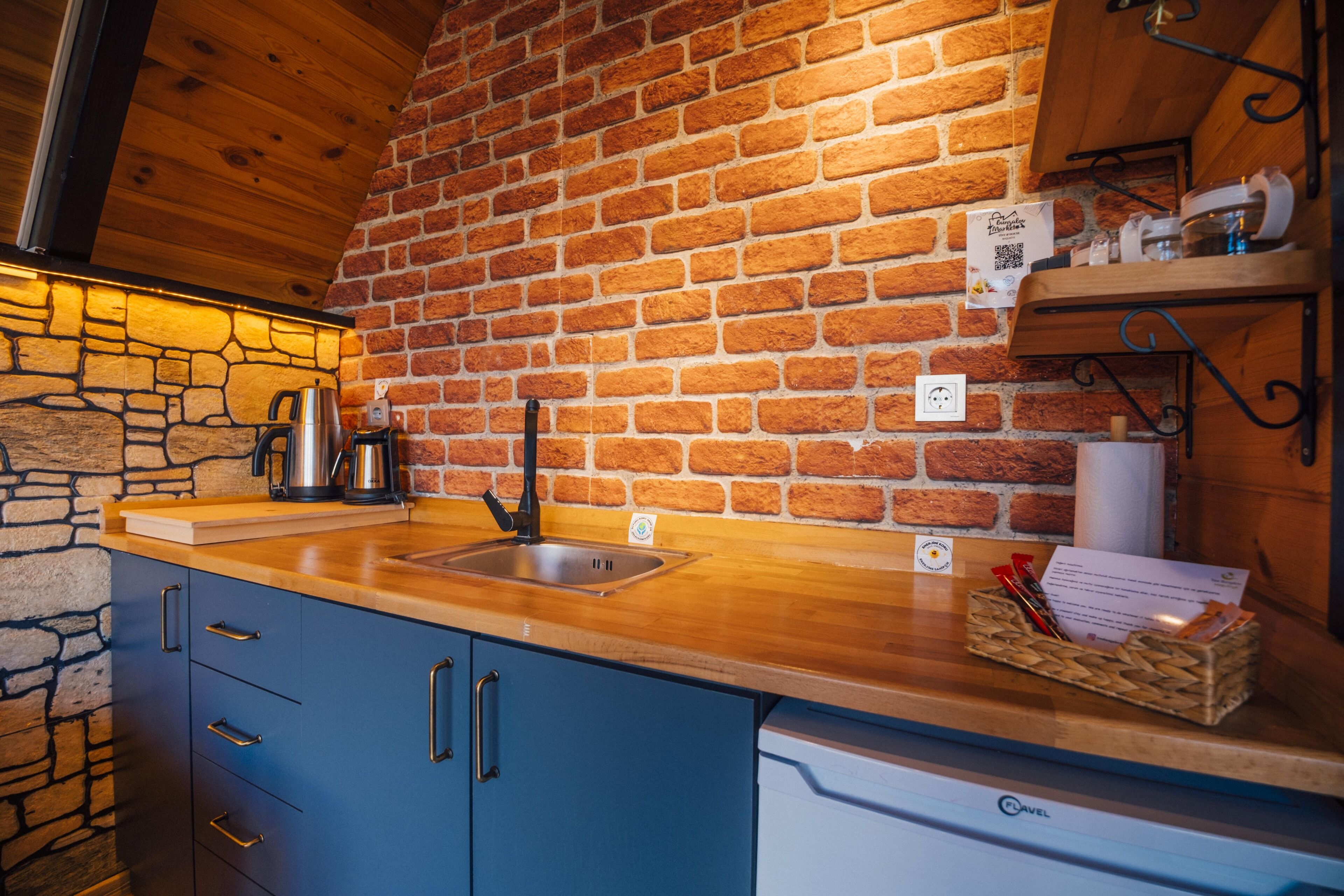 A kitchen with a brick wall, wooden countertop, and a coffee machine.