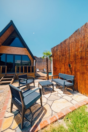 Un área de estar exterior moderna con piscina, terraza de madera y cerca de bambú.