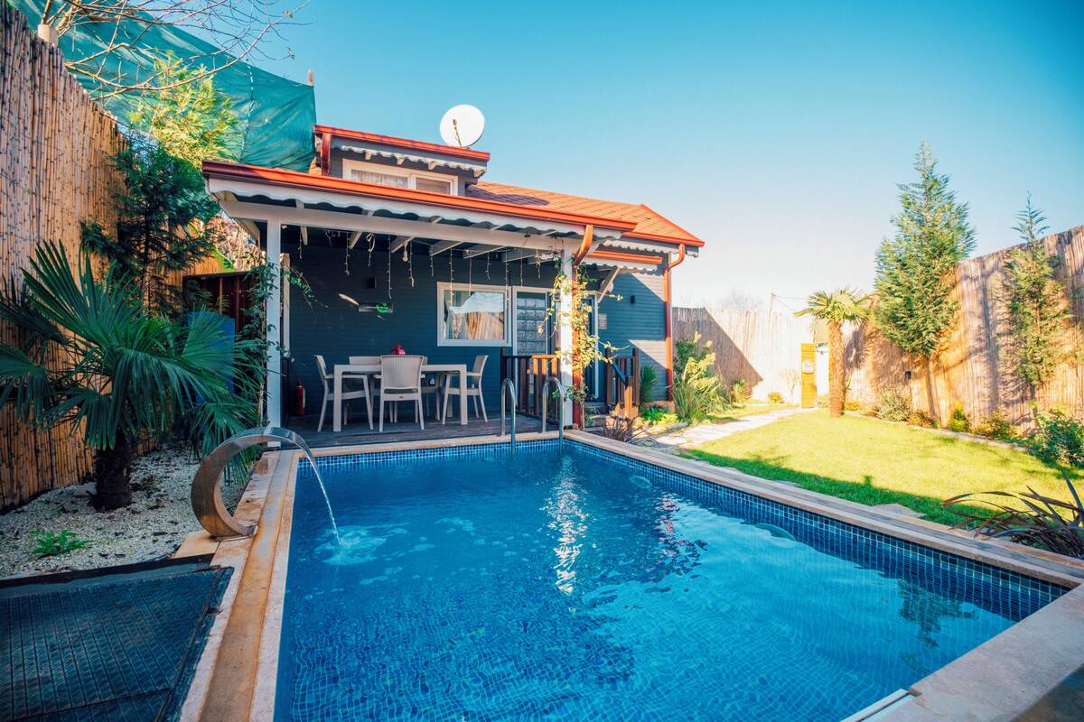 En trädgård med en pool, en täckt uteplats och ett hus med en satellitmottagare.