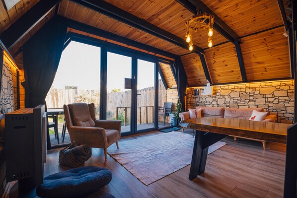Un intérieur chaleureux et rustique, avec un mur en pierre, un plafond en bois et une grande table à manger.
