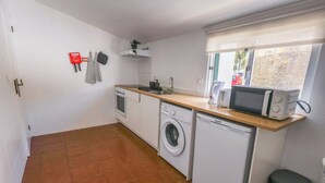 Cocina compacta con lavadora, lavavajillas, microondas y ventana con vistas.