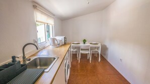 Una cocina compacta con lavamanos, encimera y un pequeño comedor con sillas y mesa.