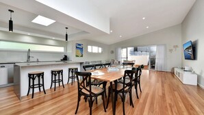 Una cocina amplia con una isla central, suelo de madera y luminarias modernas.