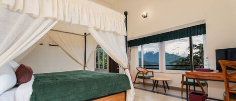 A bedroom with a four-poster bed, a desk, and a chair.