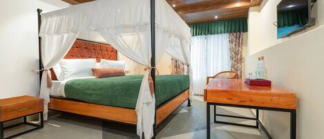 A four-poster canopy bed with a green bedspread, wooden headboard, and white pillows.