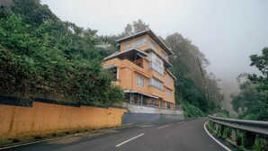 A multi-story hotel with a modern design, located on a hillside with lush greenery. - Summit Bougainvillea Tea Resort (Kurseong)