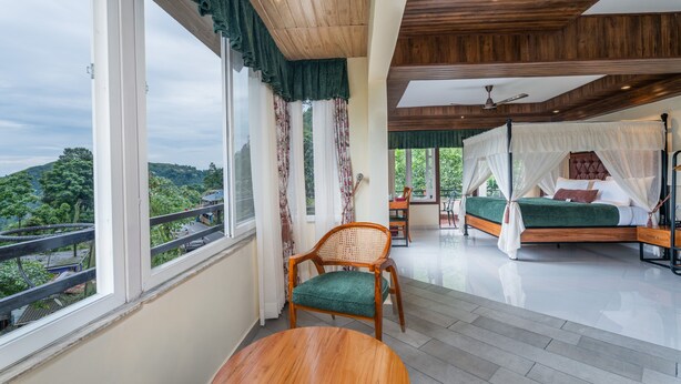 A bedroom with a canopy bed, a view of the outdoors, and a dining area with a table and chair. - Summit Bougainvillea Tea Resort (Kurseong)