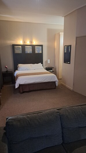 Una habitación de hotel con una cama grande, una mesita de noche, una lámpara y un cuadro en la pared.