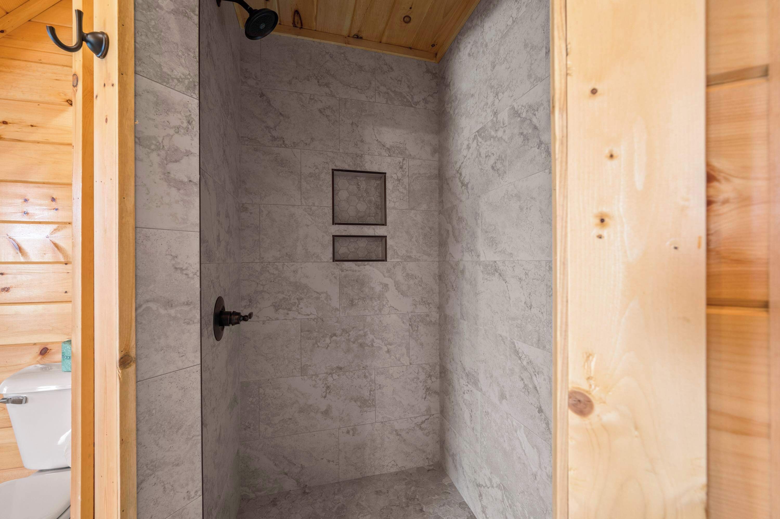 A wooden interior with a shower area featuring tiled walls and a door with a handle.