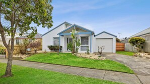 A single-story house with a front garage, a well-maintained lawn, and a tree in the foreground. - Ideally located Beach House close to picturesque reserve and beaches (Torquay)