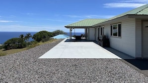 A building with a covered patio, a gravel driveway, and a view of the ocean. - Hale Lewa ~ Newer Home ~ Ocean Views ~ 30 Day Rent (Waimea)