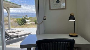 A room with a view of the ocean, a desk with a lamp, and a framed picture on the wall. - Hale Lewa ~ Newer Home ~ Ocean Views ~ 30 Day Rent (Waimea)