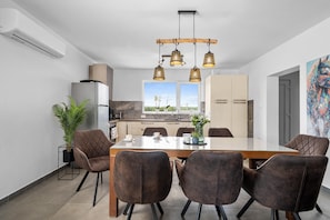 Enjoy meals in this dining area with a long table and six comfortable chairs, surrounded by a large window offering a view of the outdoors.