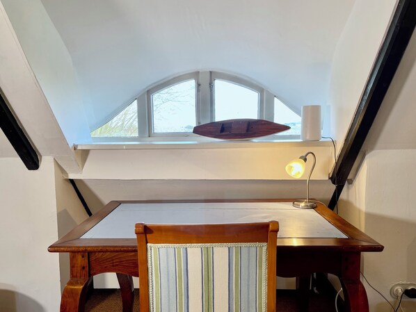 A dining area with a table, a chair, a lamp, and a skylight above.