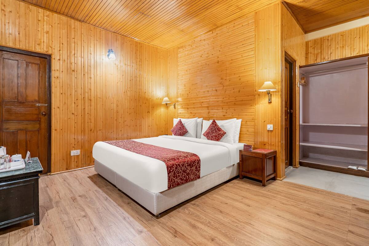 A wooden-paneled bedroom with a large bed, bedside lamps, and a wardrobe.