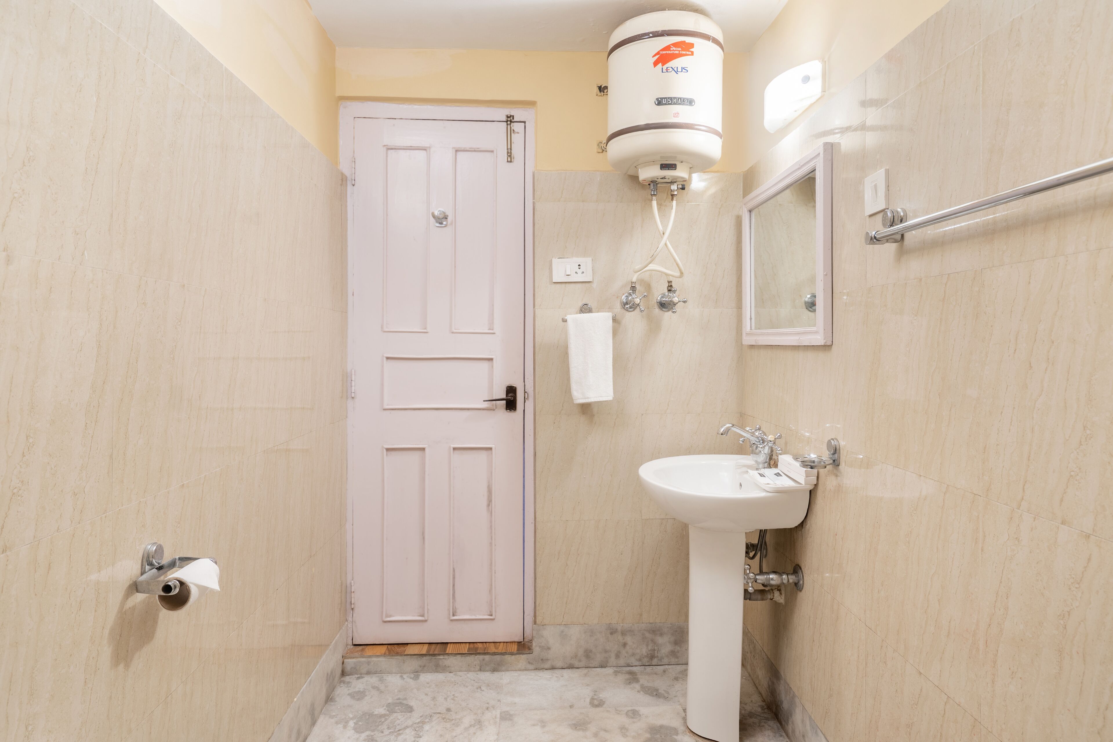Un baño con una puerta blanca, un lavabo blanco, un espejo y un calentador de agua.