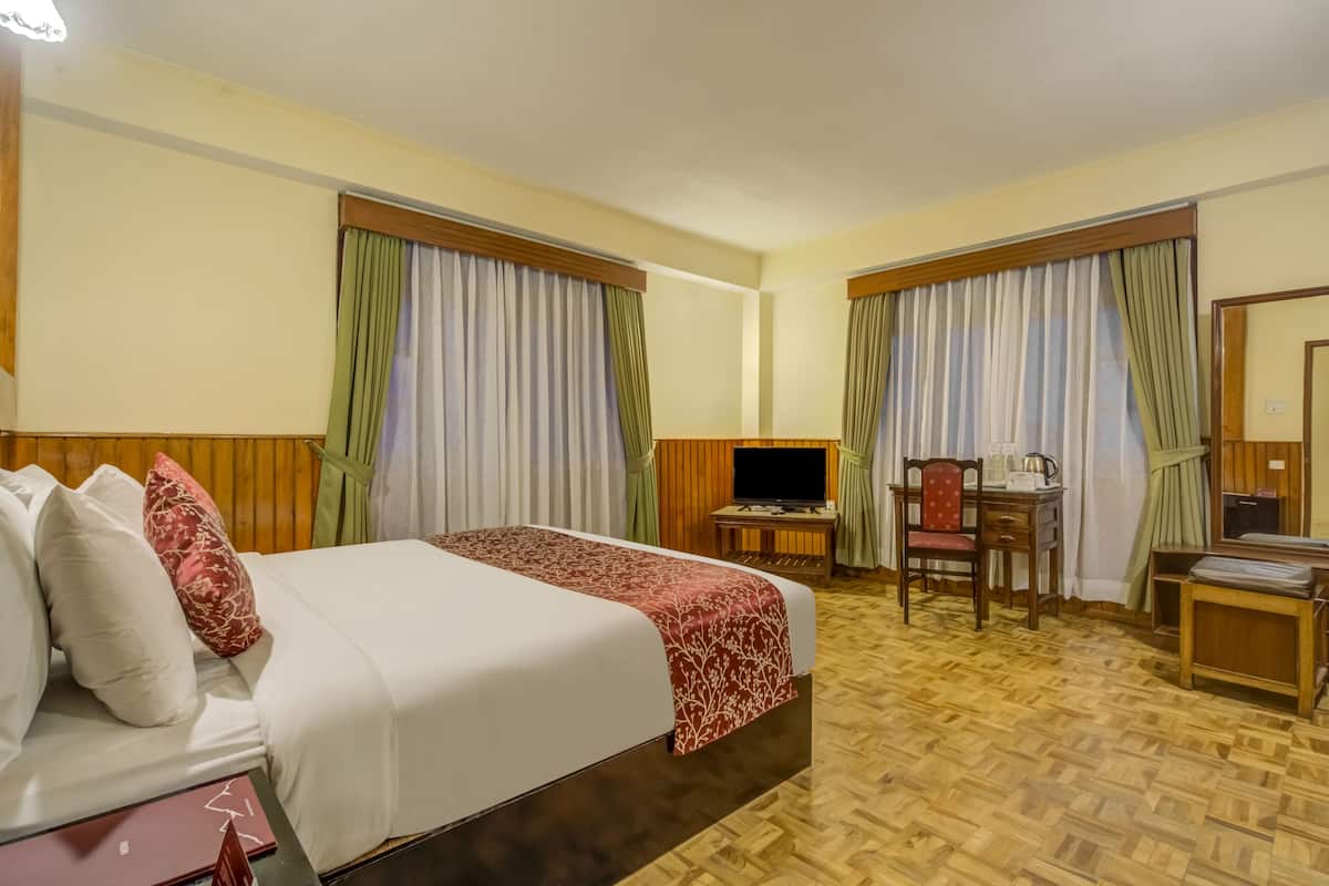A hotel room with two beds, a desk with a chair, a television, and a small table.