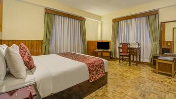 Una camera d'albergo con due letti, una scrivania con sedia, una televisione e un tavolino.