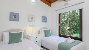 A bedroom with two beds, a nightstand, a lamp, and framed pictures on the wall. - San Lameer Villa 2810 (Southbroom)