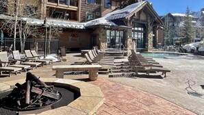 Un resort con posti a sedere all'aperto, una piscina e un braciere in pietra.