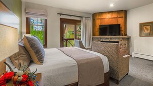 A bedroom with a bed, a TV, a fireplace, and a view of the outdoors. - Hyatt Main St Studio | Steps to Peak 9 + Downtown (Breckenridge)