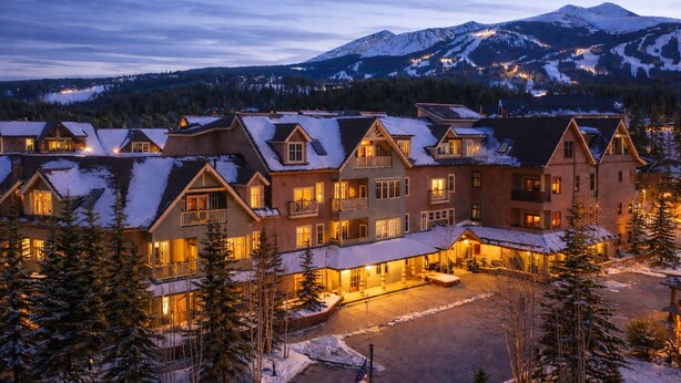 A large lodge with multiple buildings, a covered outdoor area, and a view of snow-capped mountains in the background. - Hyatt Main St Studio | Steps to Peak 9 + Downtown (Breckenridge)