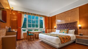 A wooden-paneled room with a bed, a desk, and a window with curtains. - Summit Gangchen Hotel (Chungthang)