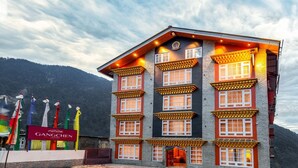 A multi-story building with traditional architectural features, including multiple windows with decorative frames and a prominent entrance. - Summit Gangchen Hotel (Chungthang)