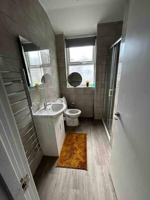 A compact bathroom with a modern design, featuring a toilet, sink, and a small window.