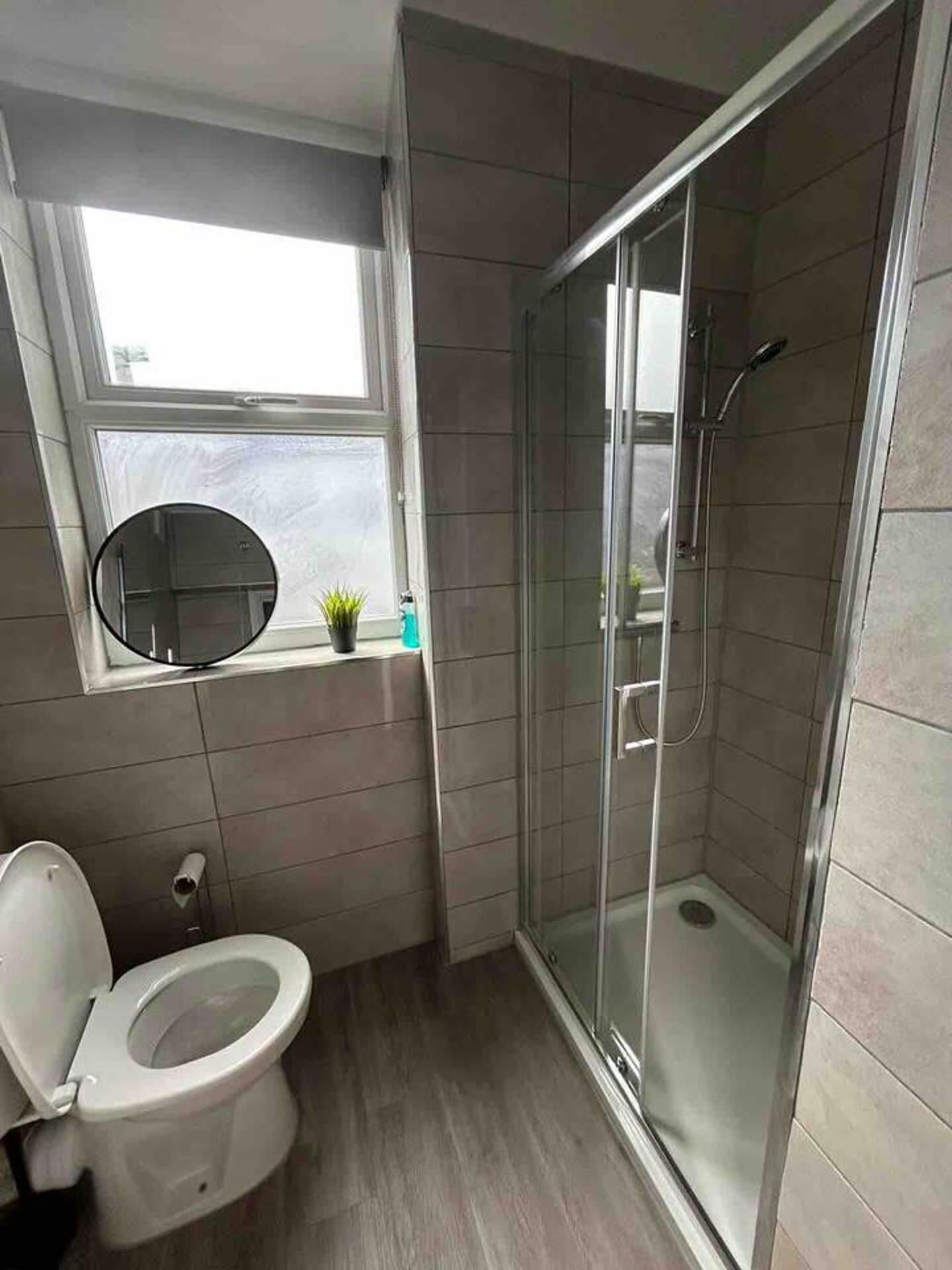A bathroom with a toilet, a shower, and a window.