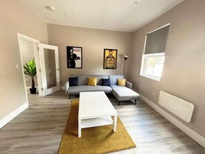 A modern living room with a grey sectional sofa, a white coffee table, and two posters on the wall. - Hidden gem Close to the City Centre Free Parking (Nottingham)