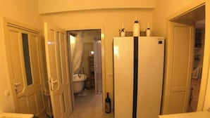 Una cocina compacta con refrigerador, un lavamanos y una zona de comedor con mesa y silla.