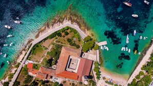 An aerial view of a coastal property with a central building, a beach, and boats in the water. - Four Bedroom apt w Patio Close to Beach and Center (Hvar)