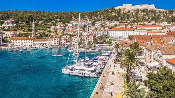 A coastal town with a marina, historic buildings, and a prominent castle on a hill. - Four Bedroom apt w Patio Close to Beach and Center (Hvar)