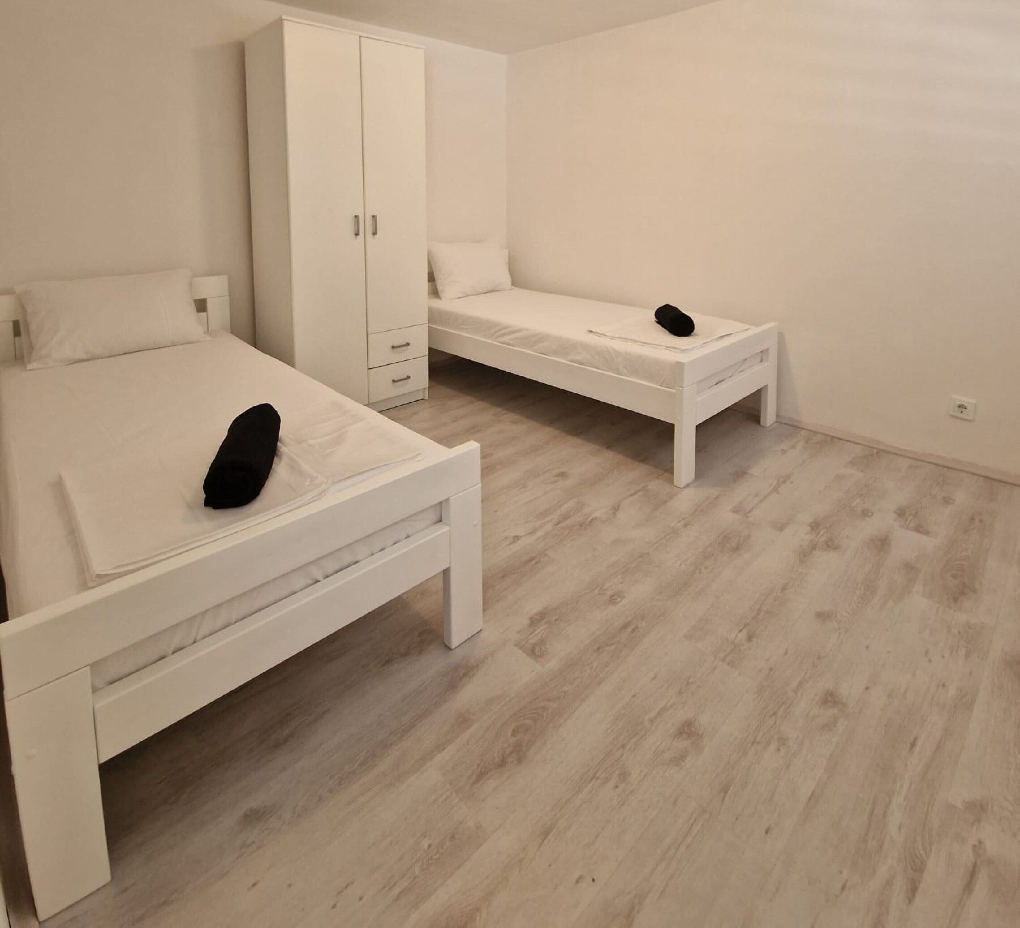 Ein Schlafzimmer mit zwei Betten, einem Kleiderschrank und einem kleinen Tisch.