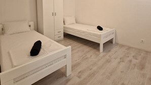 A bedroom with two beds, a wardrobe, and a small table. - Four Bedroom apt w Patio Close to Beach and Center (Hvar)