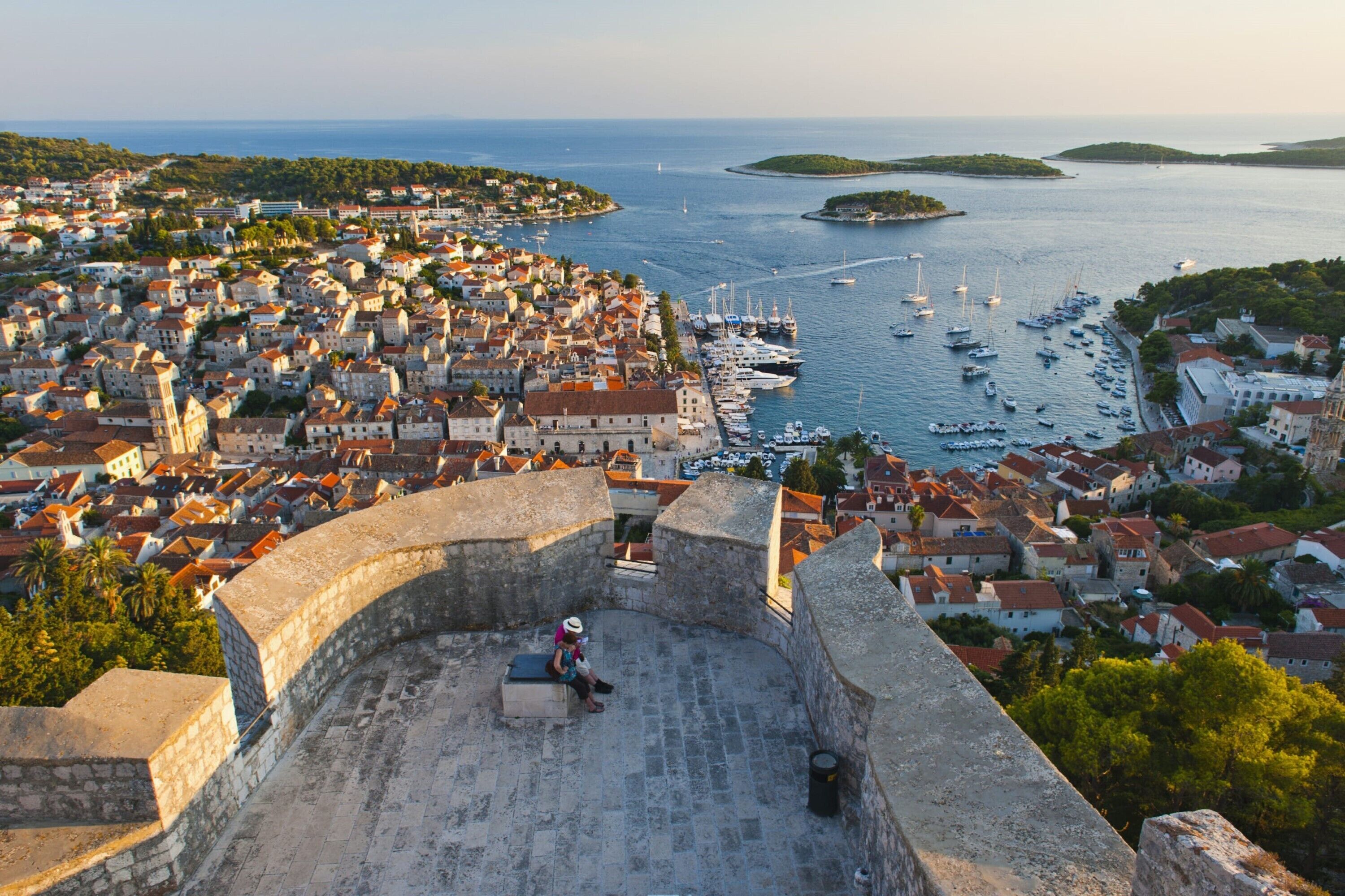 A historic stone fortification overlooking a coastal town with a marina.