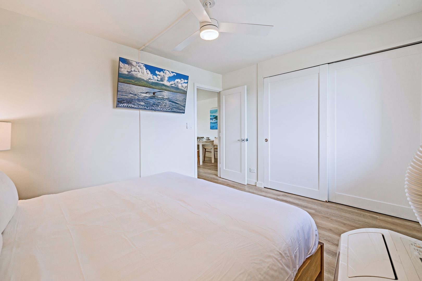 A bedroom with a bed, a ceiling fan, a wardrobe, and a door leading to a bathroom.