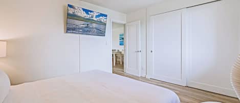 Une chambre à coucher comprenant un lit, un ventilateur de plafond, une armoire et une porte donnant sur une salle de bain.
