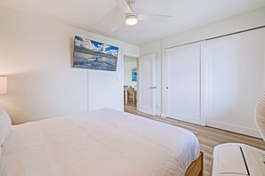 Un dormitorio con cama, ventilador de techo, armario y puerta que da a un baño.
