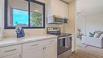 A modern kitchen with a microwave, oven, and a knife block on the counter.
