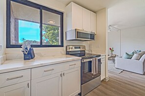 A modern kitchen with a microwave, oven, and a knife block on the counter. - Stylish 1BR Condo · Walk to Kahana Beach (Lahaina)