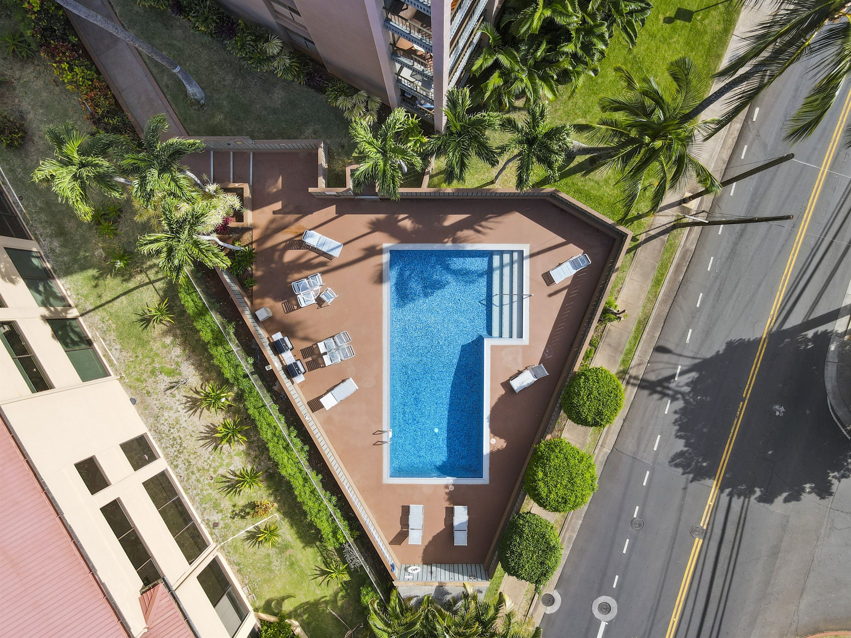 Vista aérea de una piscina en la azotea con tumbonas y una pequeña terraza.