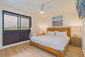Ein Schlafzimmer mit einem hölzernen Bett, einem Deckenventilator, einem Fenster mit Ausblick und einem Bild an der Wand.